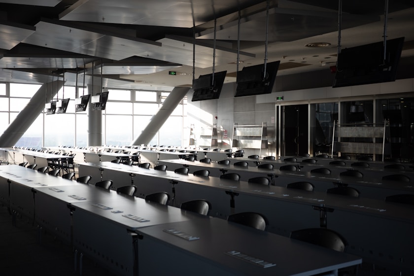 Rows of empty desks in a modern conference room.