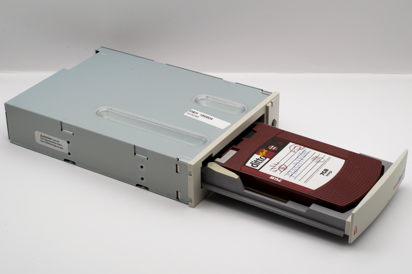 Vintage computer backup tape drive with open tray, showcasing retro technology.